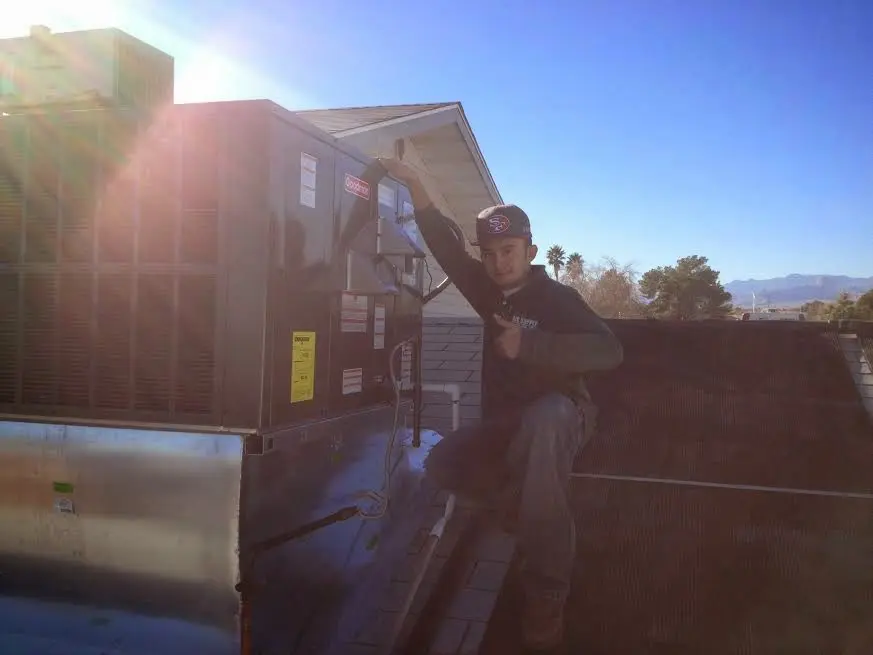 HVAC technician performing Air Duct Repair on a rooftop unit in Bedford